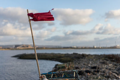 Red flag on beach against sky