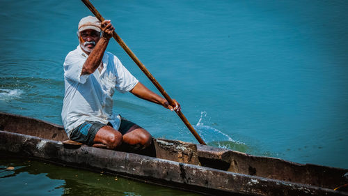 Man sitting on boat against sea