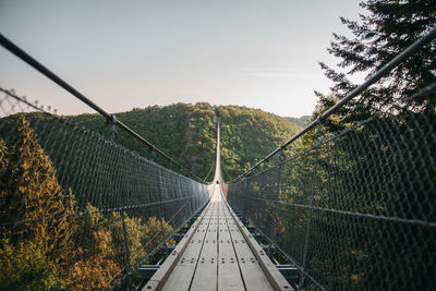 Footbridge amidst plants against sky