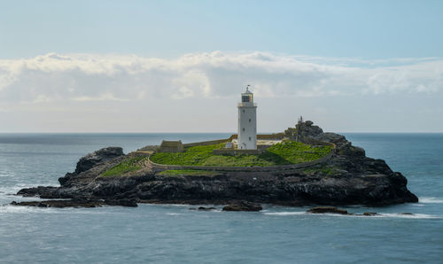 Lighthouse by sea against sky