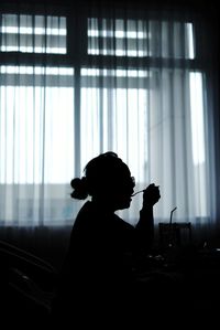 Side view of silhouette man photographing against window