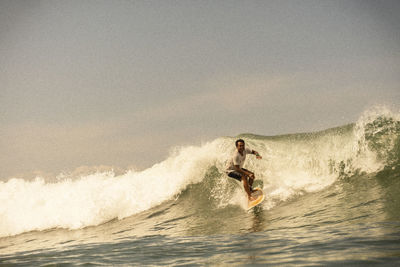 Man surfing in sea against sky