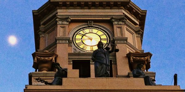 Low angle view of clock tower against blue sky