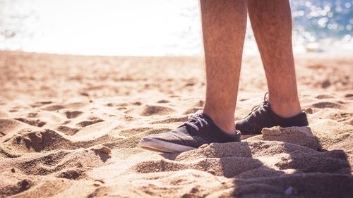 Low section of man standing on beach