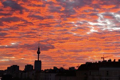 Silhouette of buildings against cloudy sky during sunset