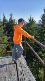 Boy standing by railing against clear sky