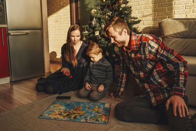 Cheerful family playing board game on floor at home