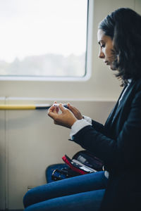 Side view of woman looking through window