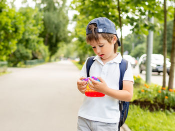 Cute boy wearing cap playing with toy outdoors