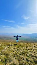 Rear view of man with arms raised against sky