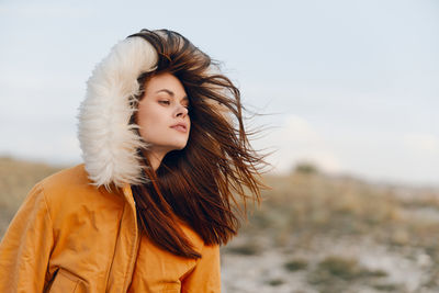 Portrait of young woman standing against sky