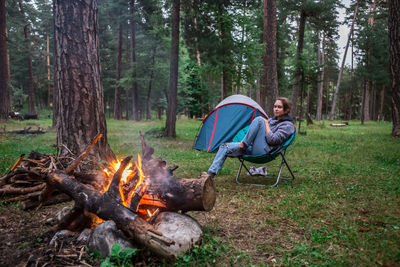 Man sitting by campfire in forest