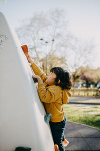 Side view of child climbing wall at playground