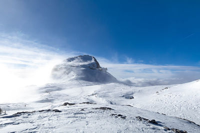 Dolomites - cima rosetta seen from tduring winter season with snowy landscape and foggy  blue sky.