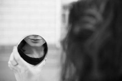 Close-up portrait of woman holding glass with reflection