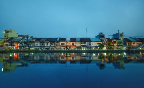 Reflection of buildings in lake against blue sky