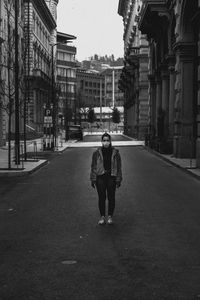 Woman standing on road amidst buildings in city