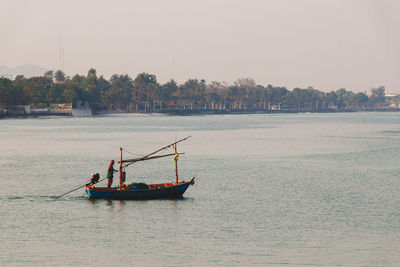 Men fishing in sea against clear sky