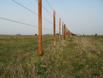 Wooden fence on field against clear sky