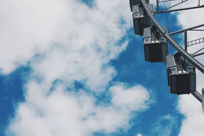 Low angle view of ferris wheel against cloudy sky