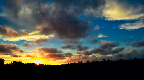 Silhouette landscape against dramatic sky during sunset