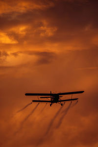 Low angle view of airplane against sky during sunset