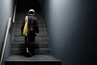 Rear view of boy moving up on steps in building