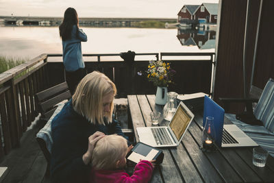 Woman teaching daughter in using digital tablet while friend talking on mobile phone