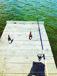 High angle view of beer bottles with fishing rod on pier