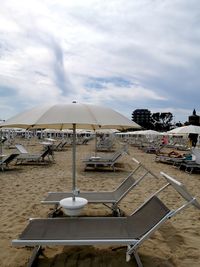 Chairs and tables on beach against sky