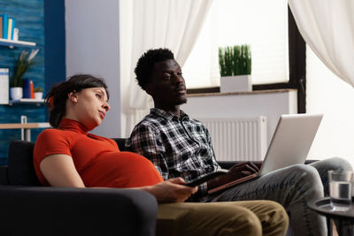 Pregnant woman watching movie while sitting on sofa