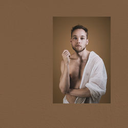 Portrait of young man standing against wall