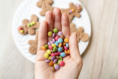 Cropped image of mother hand holding candies over cookies