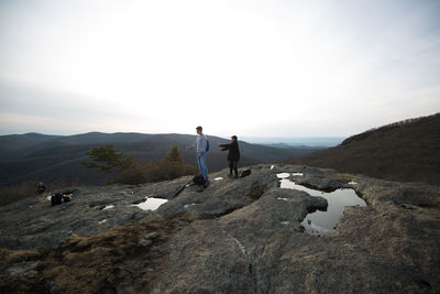 Man standing on rock against sky