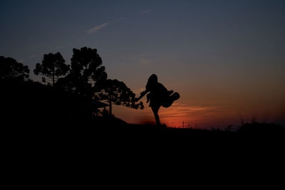 Silhouette man on landscape against sky during sunset