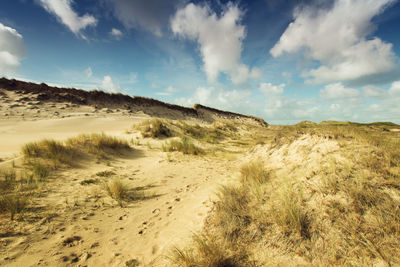 Scenic view of sand dunes against sky