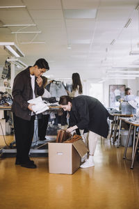 Male and female fashion designer unboxing cardboard box at workshop