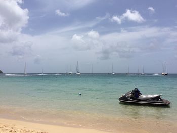 Boats in sea against cloudy sky