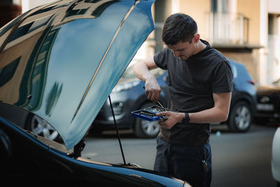 A young man takes a screwdriver out of a car repair box.