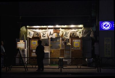 Full length of man standing against illuminated wall at night