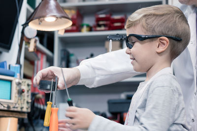 Grandfather and boy repairing computer part on table at home