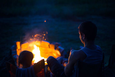 People sitting by bonfire at night