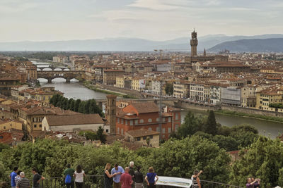 Panoramic view of people by river in city against sky