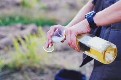 Midsection of person pouring drink in glass