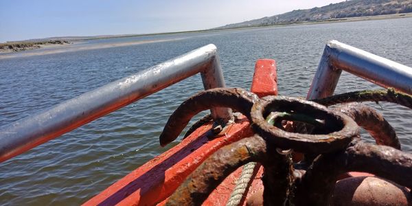 Close-up of rusty railing by sea against sky