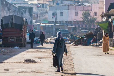 Rear view of people walking on street against buildings in city