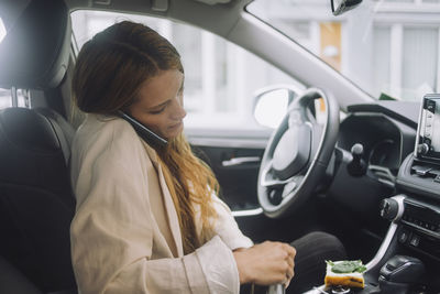 Female professional talking on smart phone while sitting in car