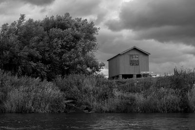 Stilt house by lake against sky