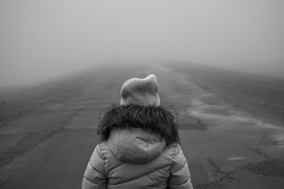 Rear view of girl in fog against sky