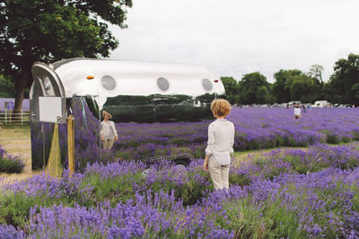 Rear view of woman standing against chrome trailer with reflection on lavender field